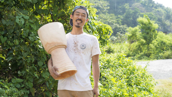 自作したジャンベを持ち、笑う木村さん。作成した後、木を乾燥させて太鼓は完成する。